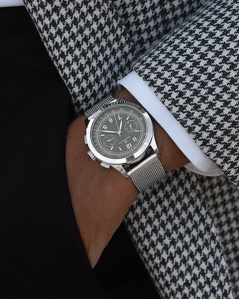 En rund herrklocka i rodiumpläterat silver från WALDOR & CO. med svart urtavla i brass. Seiko urverk. Modellen är Chrono 39 Cinque Terre. 39mm