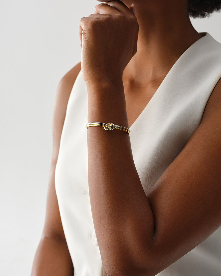 A Bangle in 14k-gold plated and silver polished 316L stainless steel from Waldor & Co. One size. The model is Dual Knot Bangle Polished.