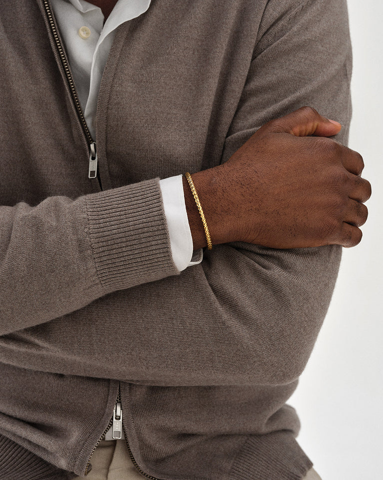 A polished stainless steel bangle in 14k gold plated from Waldor & Co. One size. The model is Noble Bangle Polished