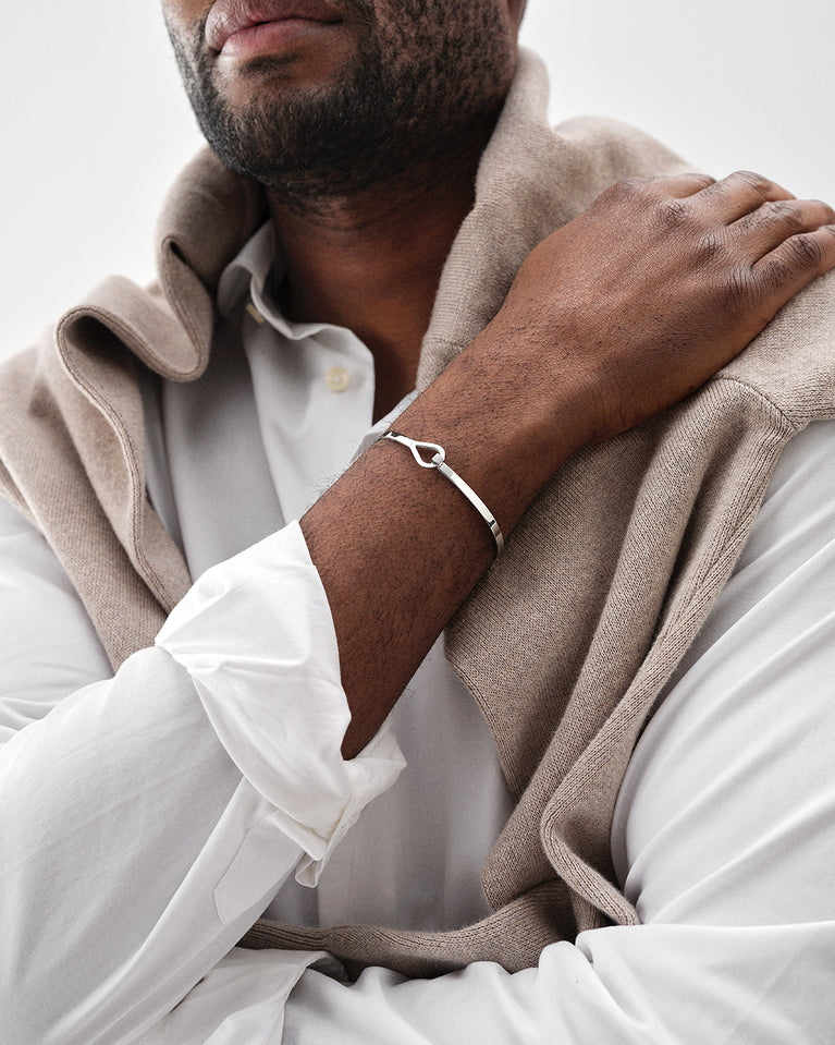 A polished stainless steel bangle in silver from Waldor & Co. The model is Signature Bangle Polished