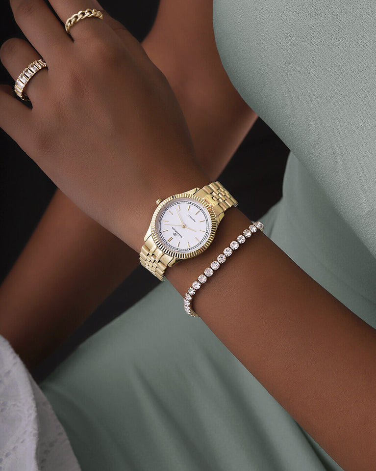 A round womens watch in 14k gold from Waldor & Co. with white sunray dial and a second hand. Seiko movement. The model is Imperial 32 Positano 32mm.